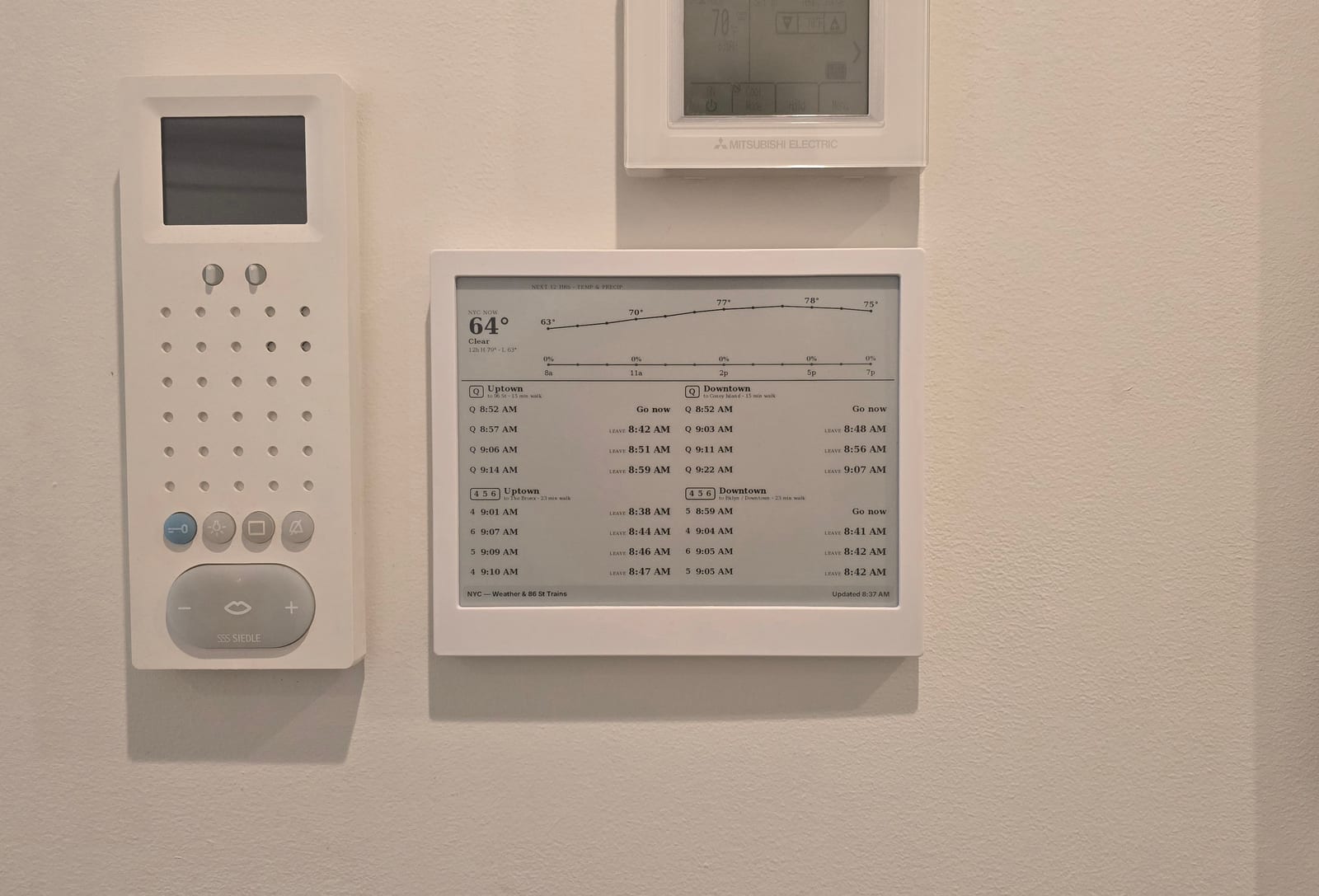 The TRMNL on the wall by the door, between the intercom and the thermostat